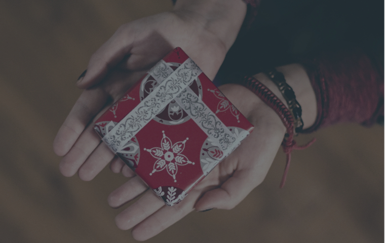 Geschenk mit weißem Einband und Weihnachtsverpackung auf zwei Handflächen gehalten