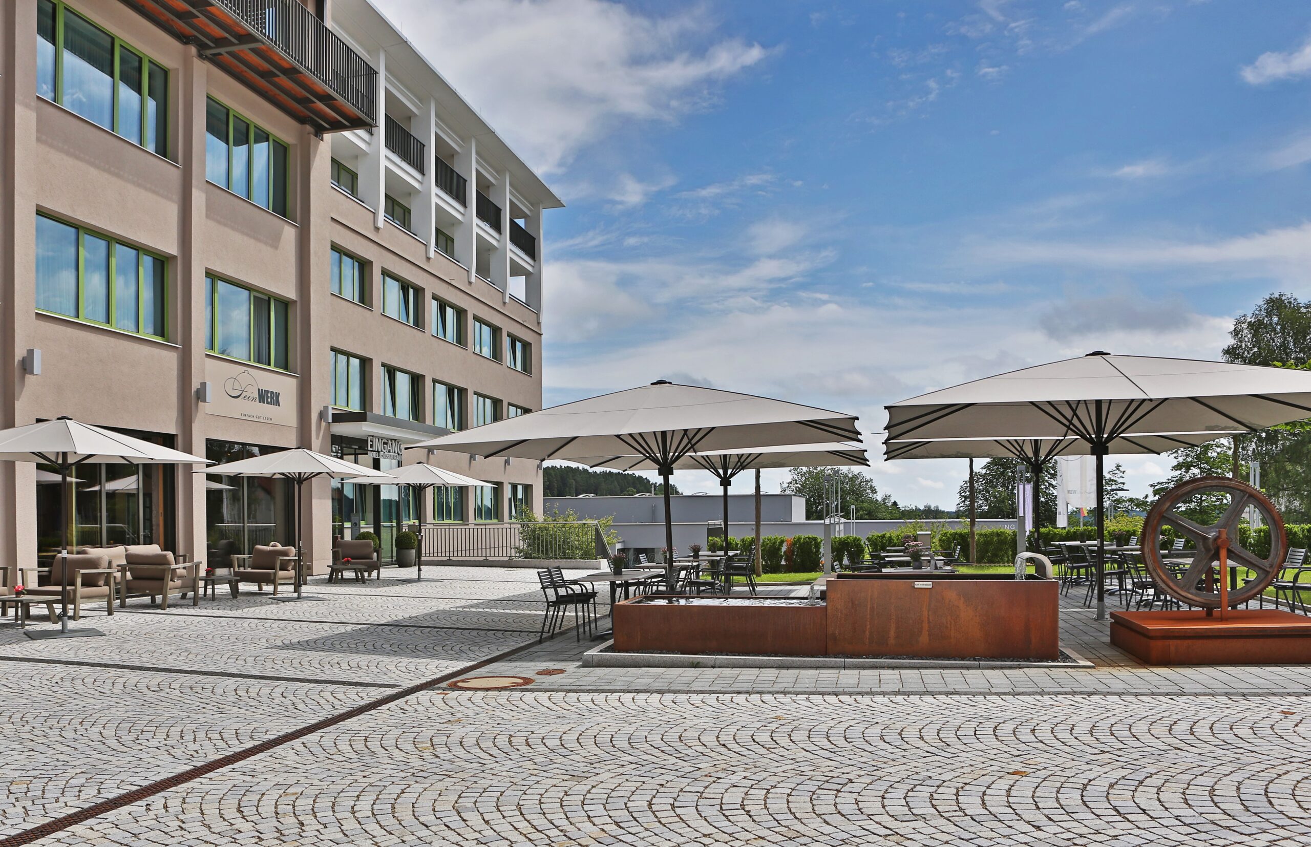 Foto der Terrasse des Restaurant Feinwerk mit Sonnenschirmen und blauem Himmel